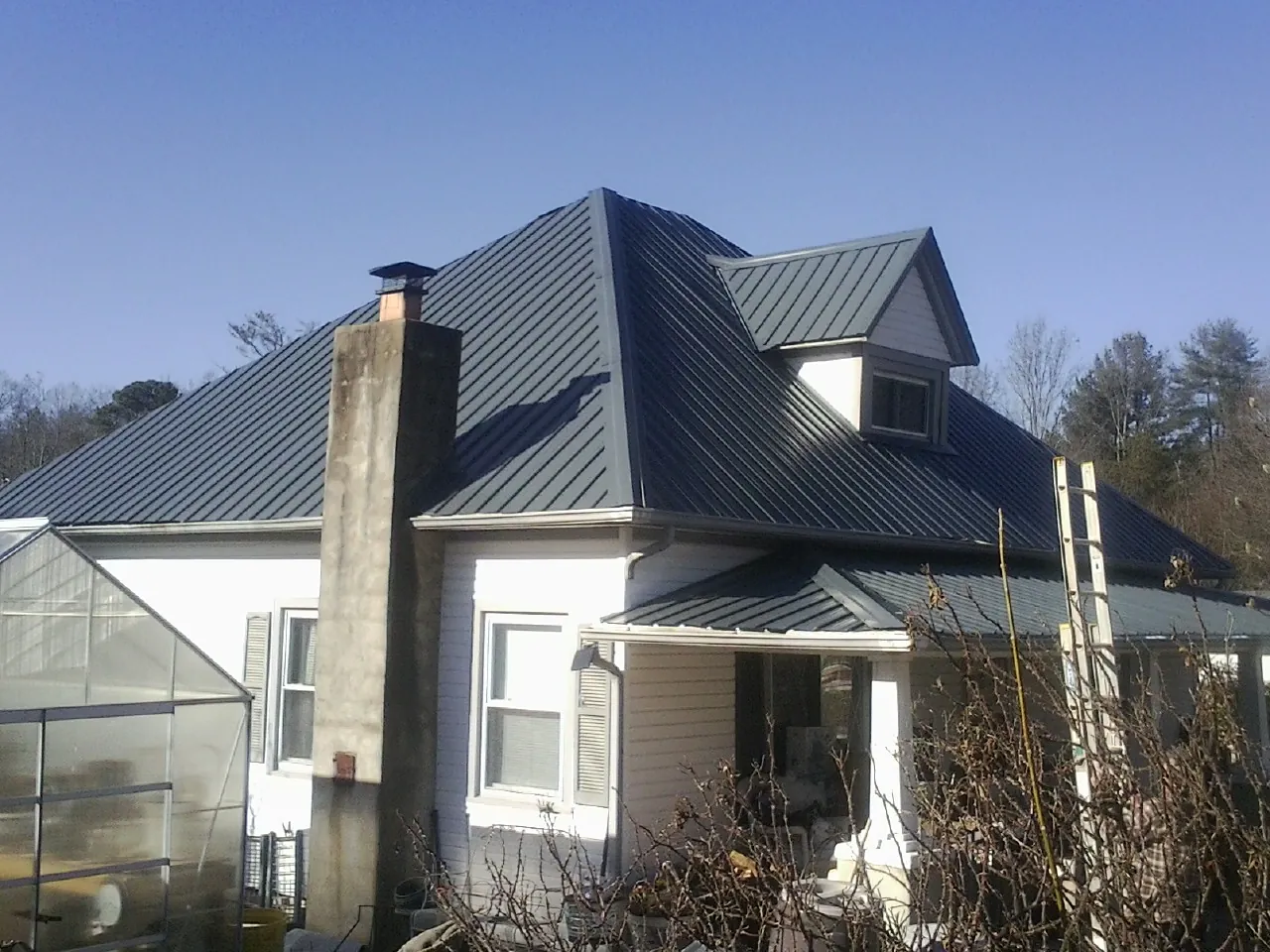 Dark blue standing seam metal roof on a white farmhouse with dormer — Slate & Tile Roof Repair by Roofing Brothers in Lakeville