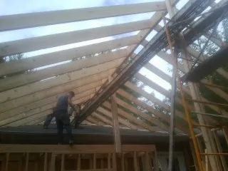 Rafters going up over a new addition with a worker on the wall in Lakeville